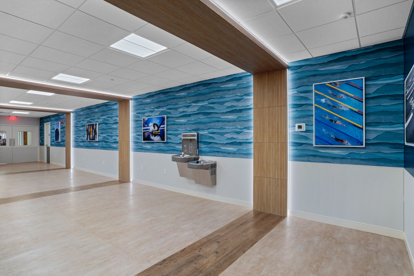 Aquatic center corridor with LED troffers and cove-lit accent walls